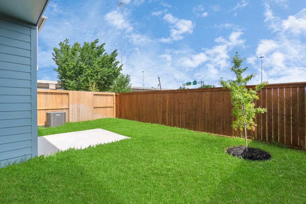 a backyard with green grass and a wooden fence