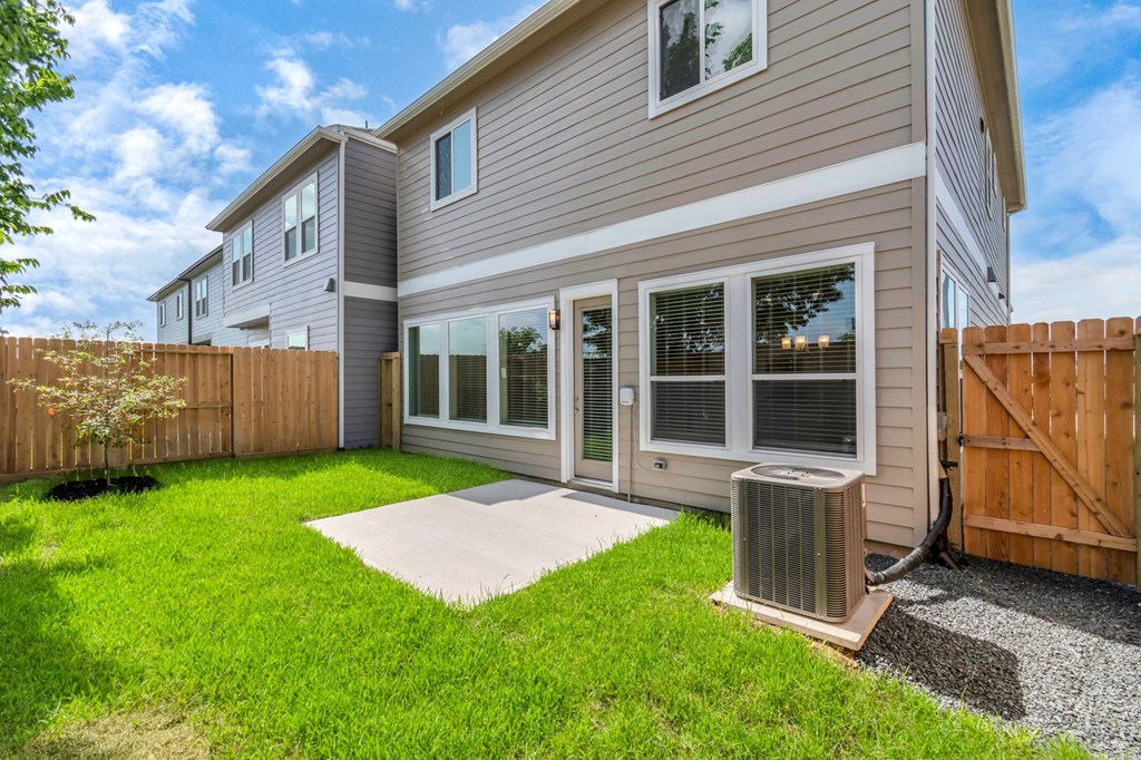 the back of a house with a yard and an air conditioner