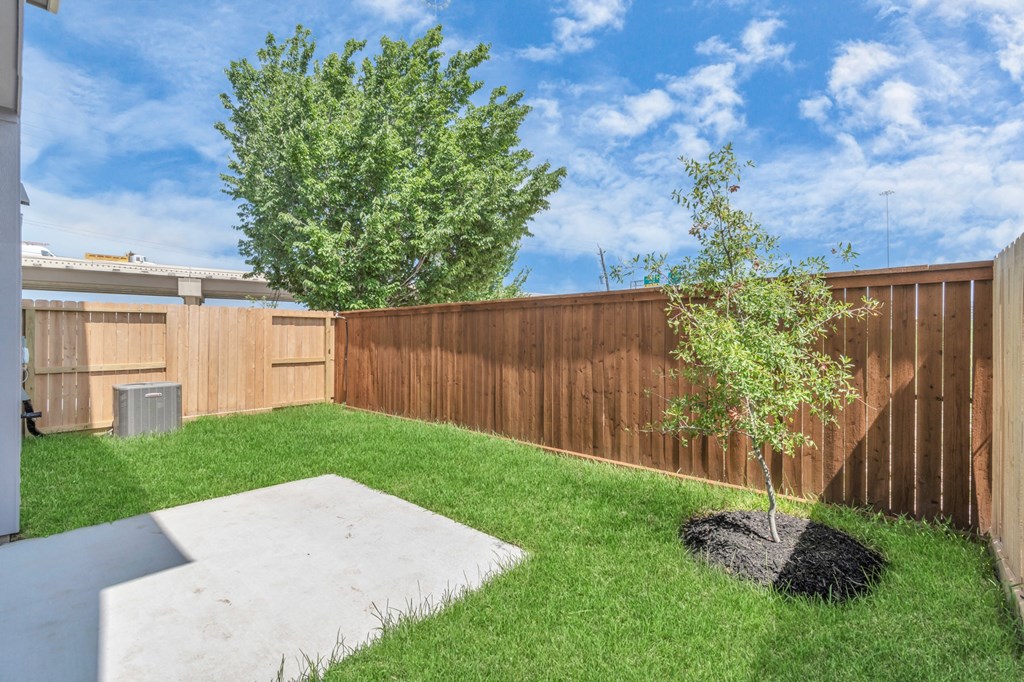 a backyard with green grass and a wooden fence