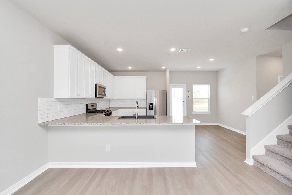 a kitchen and living room with a staircase in a house