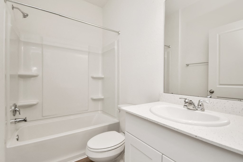 A white bathroom with a toilet, sink, and bathtub.