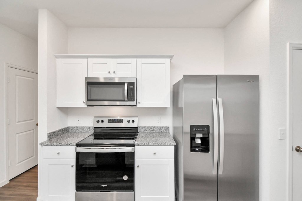 A kitchen with a stainless steel refrigerator and a microwave above the stove.