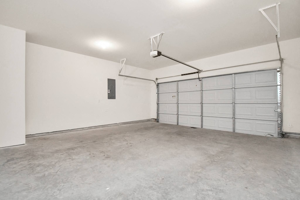 A large empty garage with a white door and a grey floor.