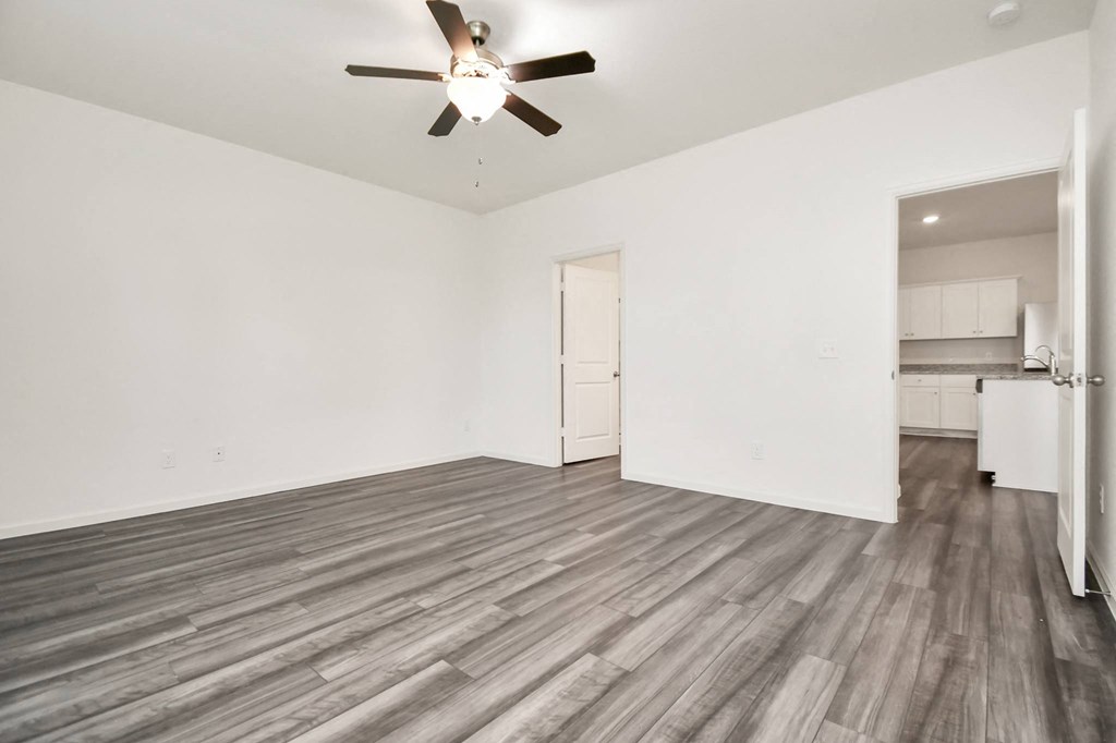 A room with a ceiling fan and wooden flooring.