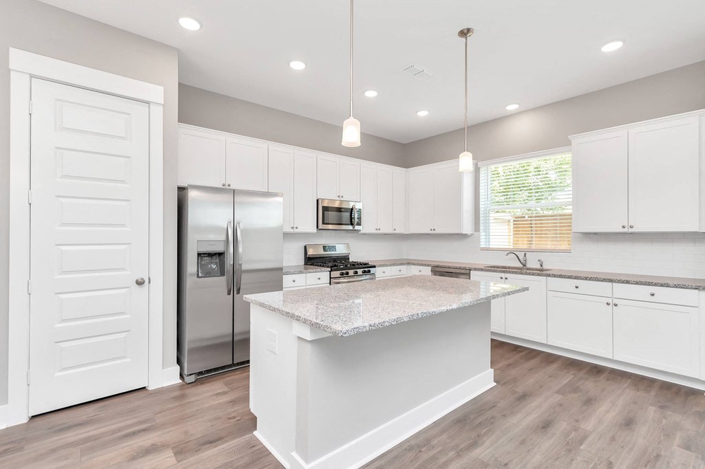 a kitchen with white cabinets and a large island with granite countertops