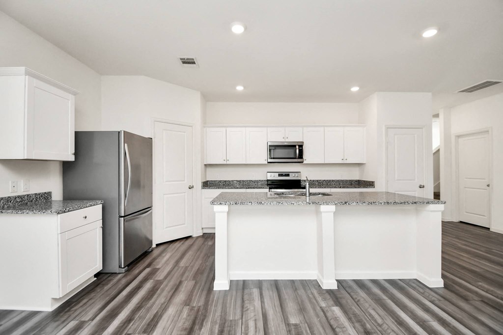 A kitchen with white cabinets and a granite countertop.