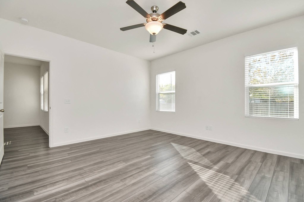 A room with a ceiling fan and wooden flooring.