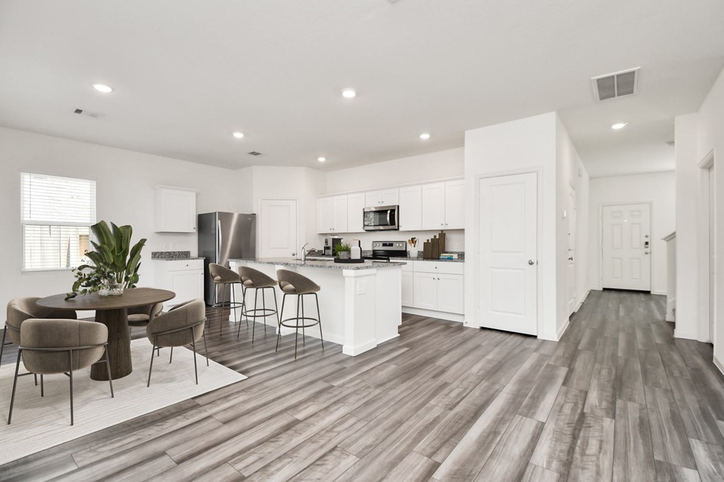 A modern kitchen with white cabinets and a wooden floor.