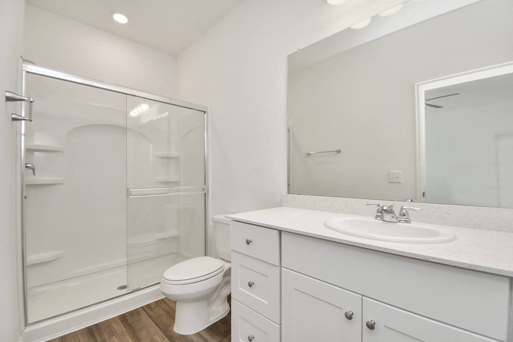 A white bathroom with a toilet, sink, and shower.