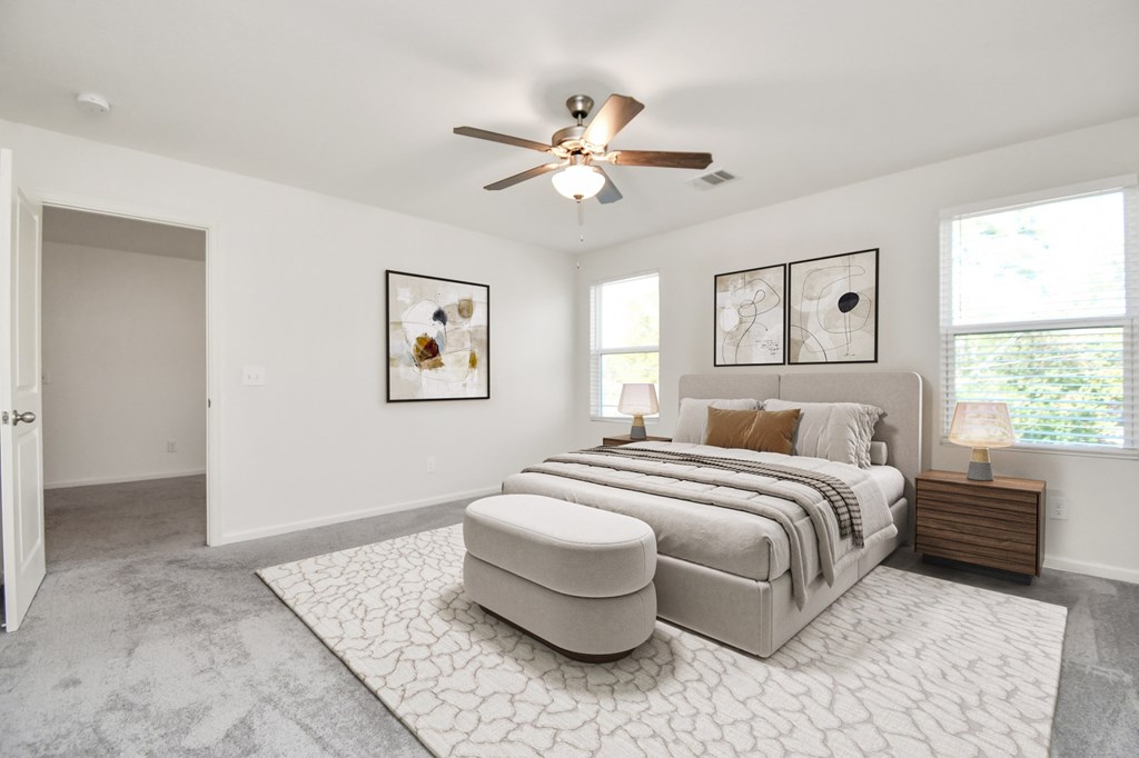 A bedroom with a large bed and a ceiling fan.