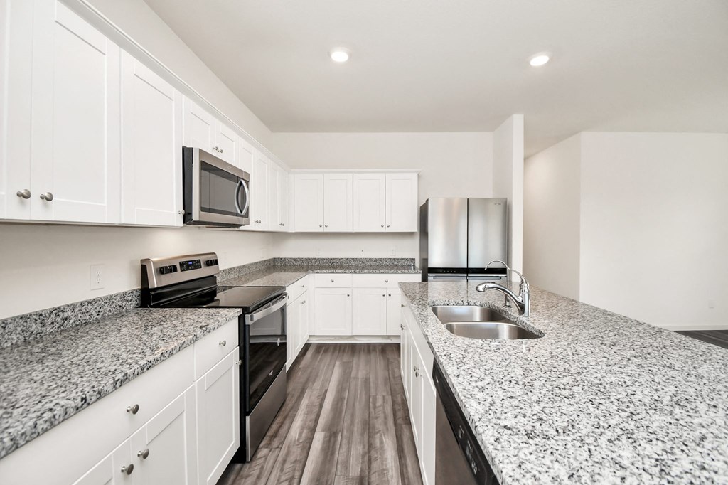 A kitchen with granite countertops and white cabinets.