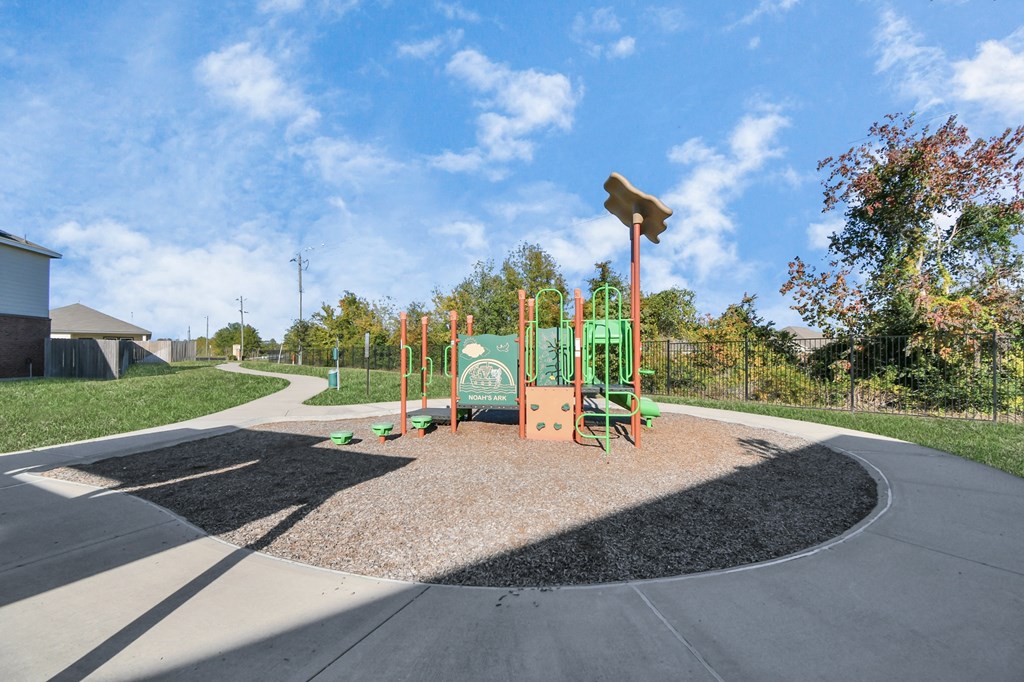 A playground with a green slide and a brown sandbox.