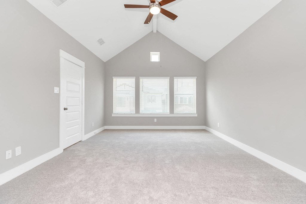 an empty bedroom with a ceiling fan and three windows