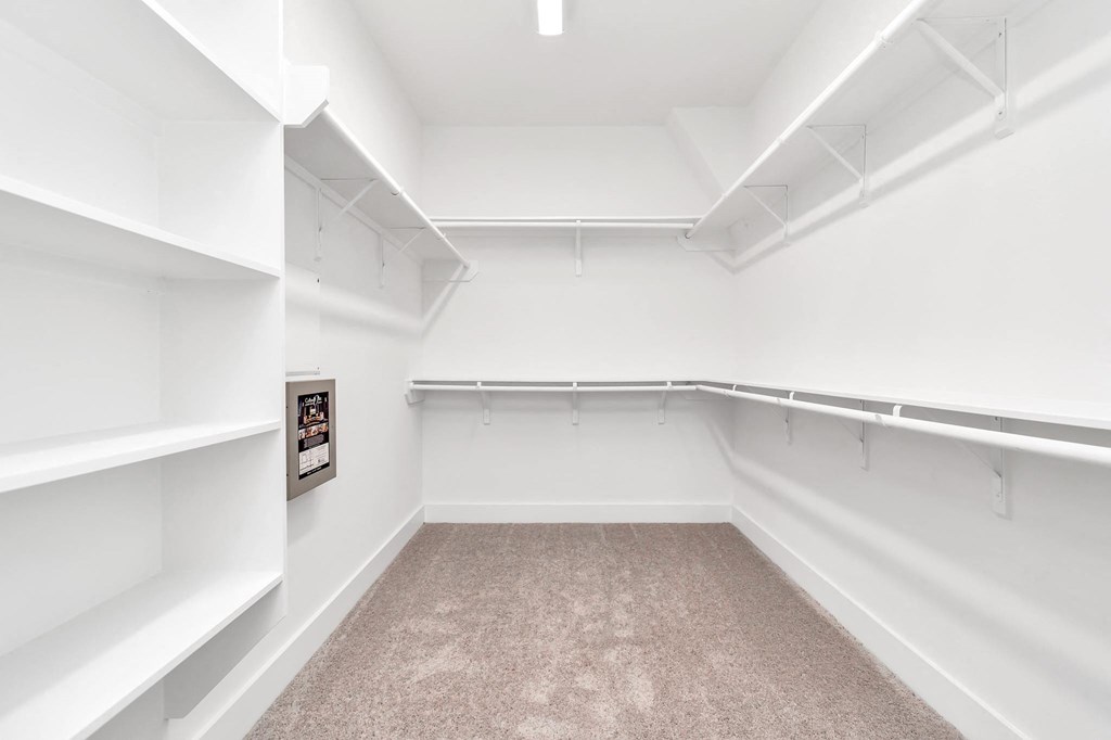 a walk in closet with white walls and white shelves