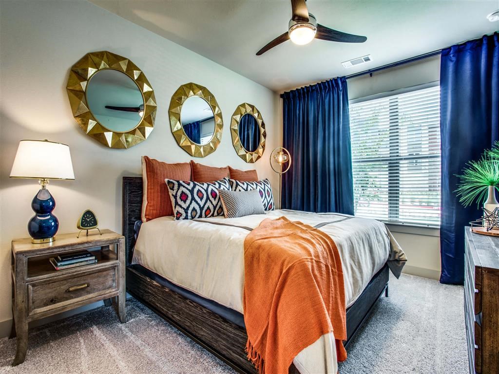 Grant Prairie TX Apartments- Spacious Bedroom With Cozy Gray Carpets, Stylish Ceiling Fan, and Large Open Window