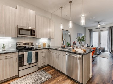 Grapevine TX Apartments - Modern Kitchen With Gray Cabinets, Black Granite Countertops, and Stainless Steel Appliances