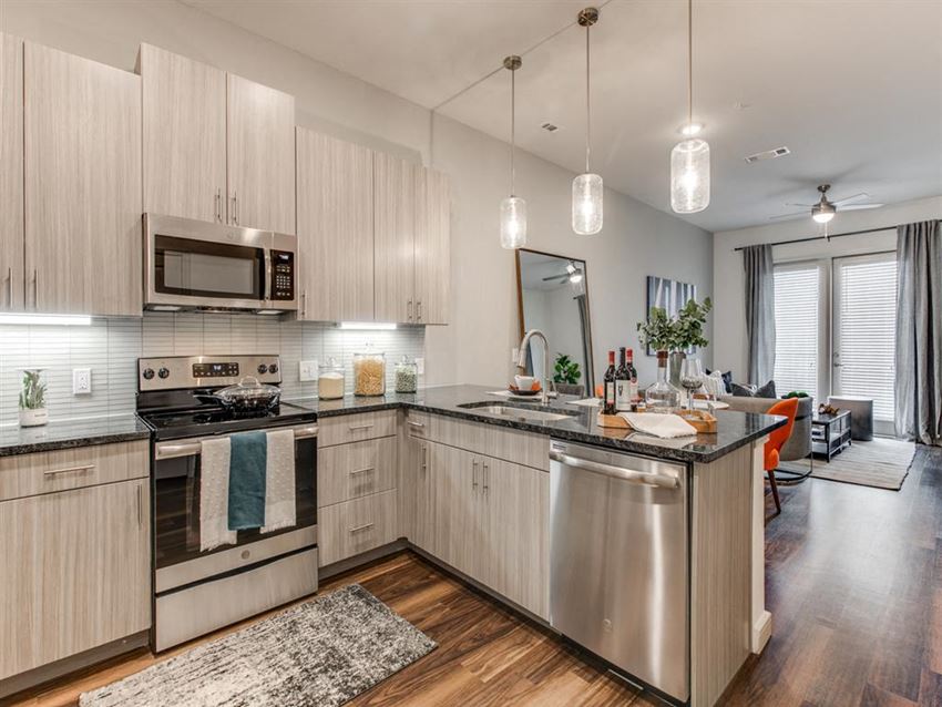 Grapevine TX Apartments - Modern Kitchen With Gray Cabinets, Black Granite Countertops, and Stainless Steel Appliances - Photo Gallery 1