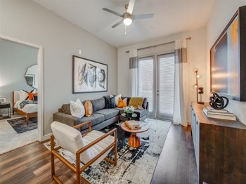 Apartments Grapevine TX - Spacious Living Room With Modern Hardwood Floors, Silver Ceiling Fan, French Doors, and Stylish Furniture - Photo Gallery 3