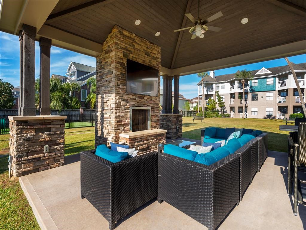 1 BR Apartments in League City, TX - Anchor at South Shore - Outdoor Lounge with Cozy Seating, a TV, a Fireplace, and a Ceiling Fan