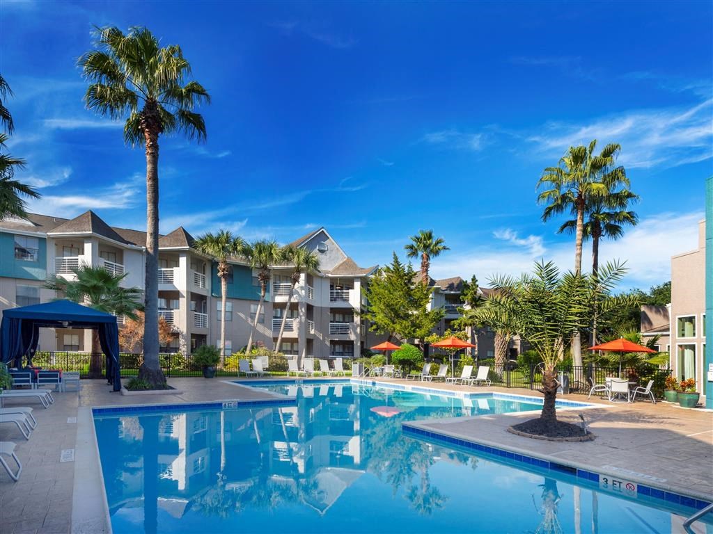 Apartments for Rent in League City, TX - Anchor at South Shore - Pool with Cabanas, Lounge Chairs, Umbrellas, and Palm Trees