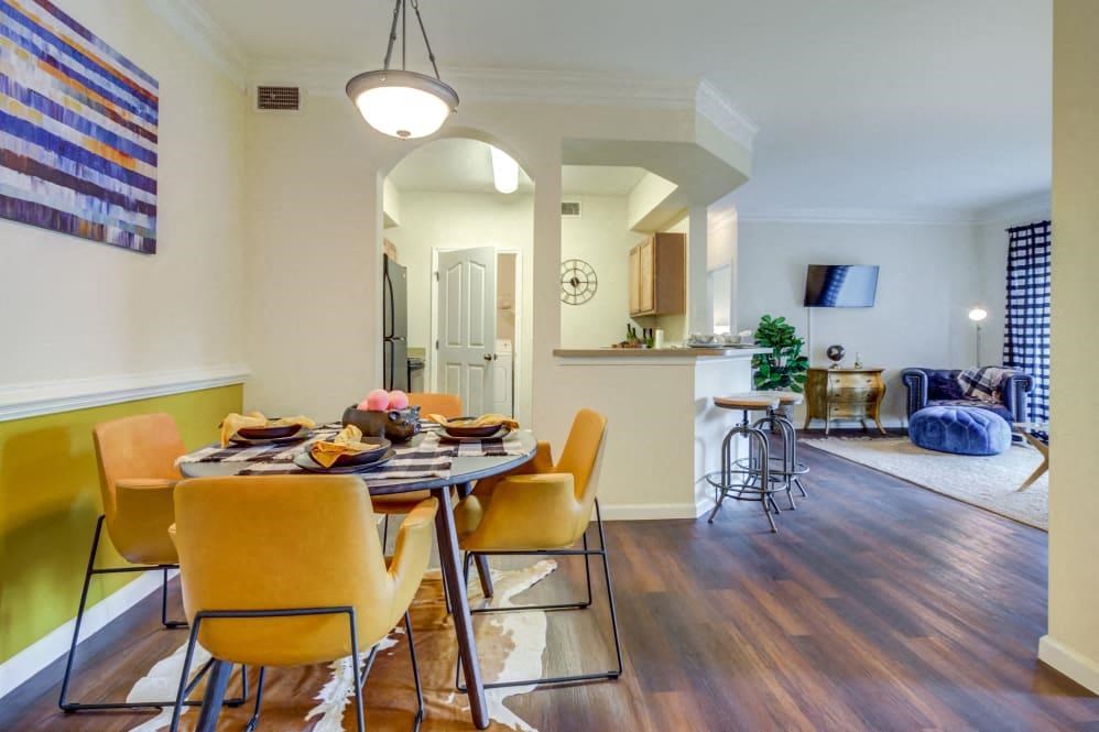 Apartments in San Antonio TX - Club at Stone Oak - Dining Room with Wood-Style Flooring, Hanging Light, and Yellow Accent Wall