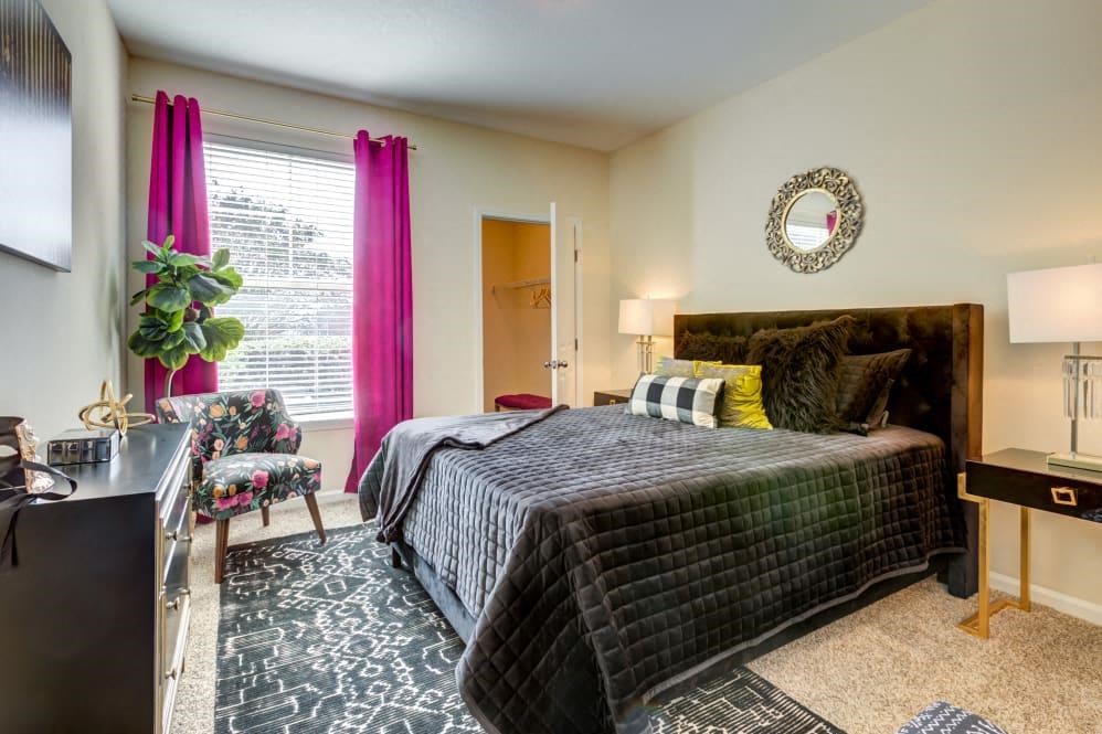 Apartments for Rent in San Antonio, TX - Club at Stone Oak - Bedroom with Plush Carpet Flooring, a Bed, Chair, Dresser, Nightstands, Lamps, Closet, and Window