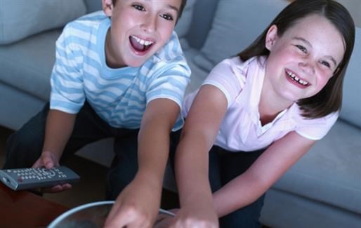 a boy and girl sitting on a couch playing a video game