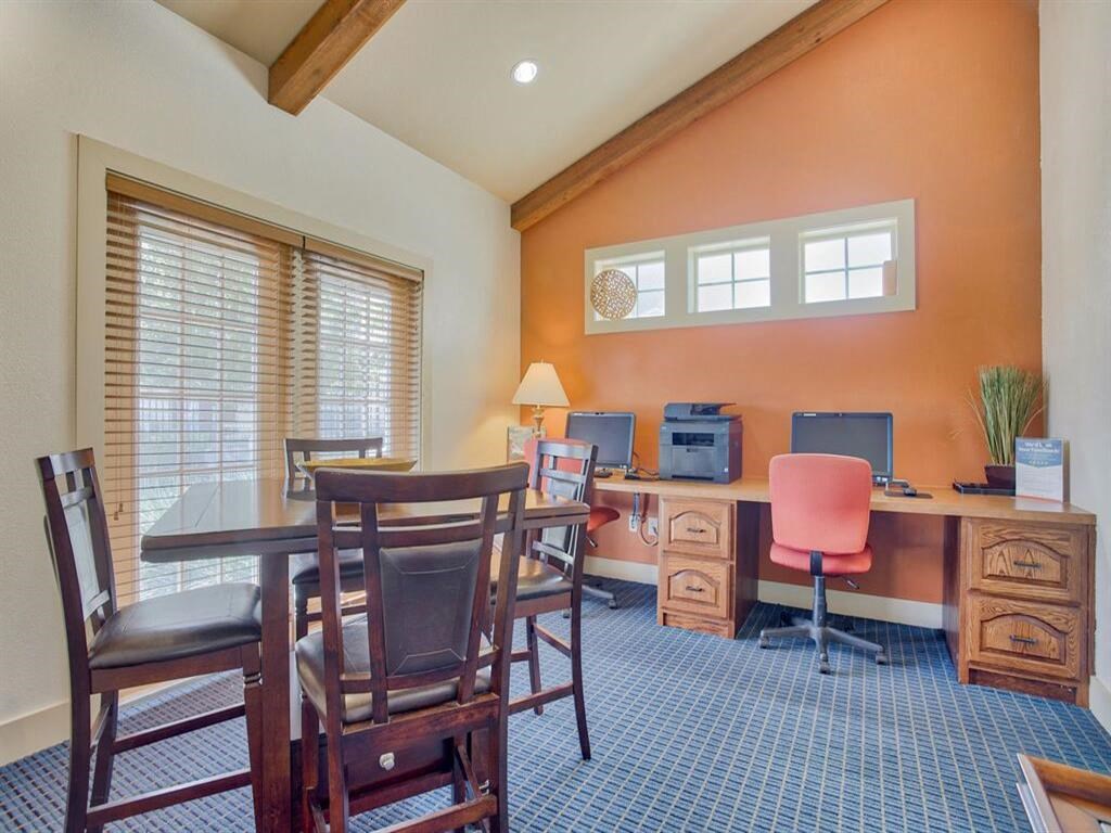 club house with computers and desks and chairs around a table and windows