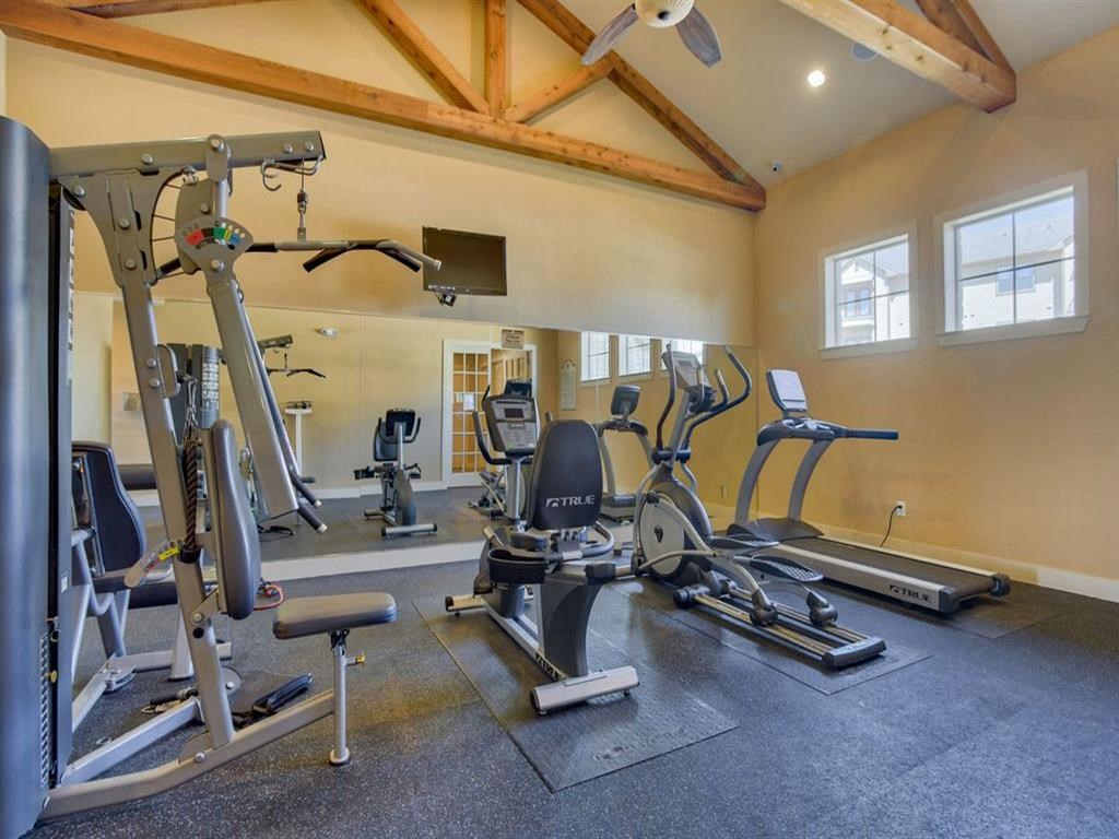 gym with a big mirror, lifting equipment, cardio equipment, and windows
