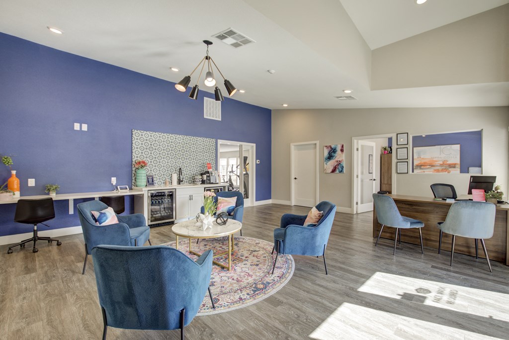 a living room with blue chairs and a table and a kitchen