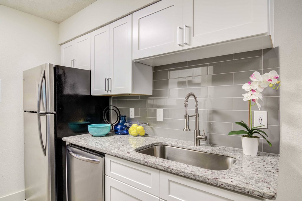 Apartments for Rent in Smyrna GA - The Arlowe Townhomes - Kitchen with White Cabinets, Stainless Steel Appliances, Granite Countertop, and Grey Tiled Backsplash