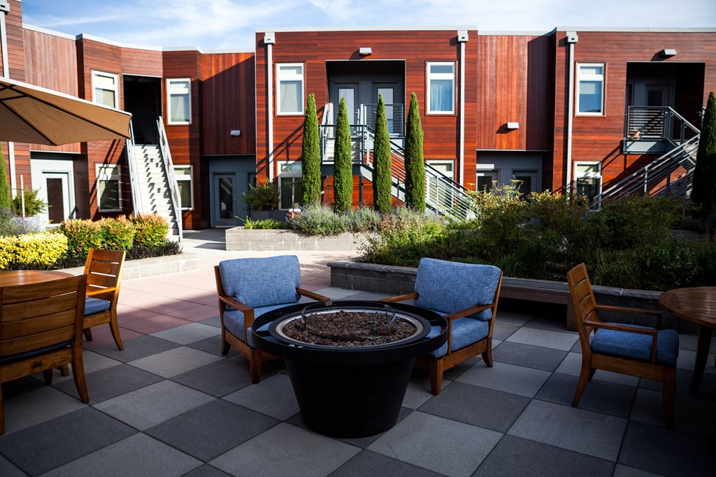 a patio with chairs and tables and a fire pit