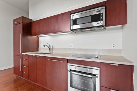 A kitchen with brown cabinets and a stainless steel oven.