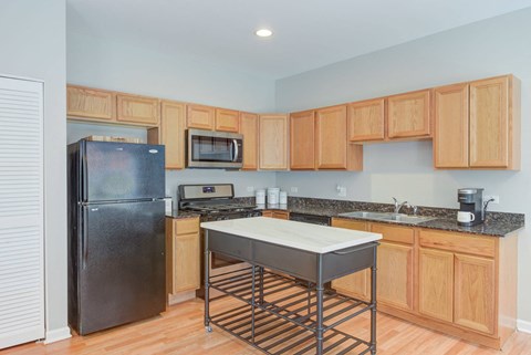 a kitchen with a stainless steel island and a black refrigerator