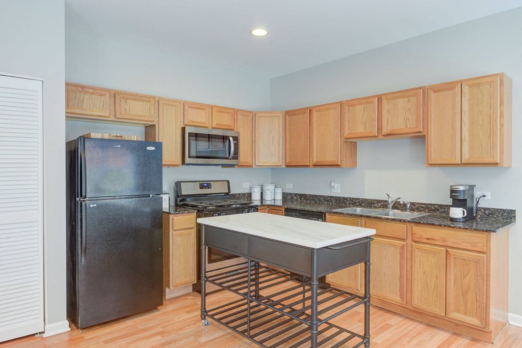 a kitchen with a stainless steel island and a black refrigerator