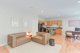 a living room with two couches in front of a kitchen
