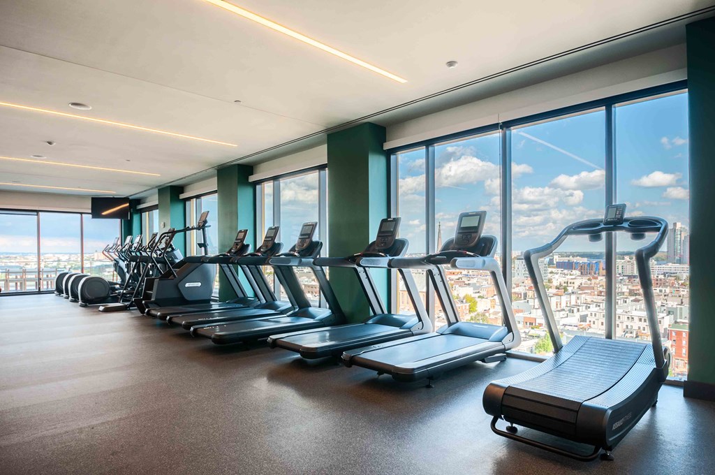 a gym with cardio equipment and a view of the city
