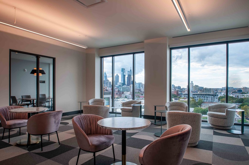 a lounge area with chairs and tables and a view of the city