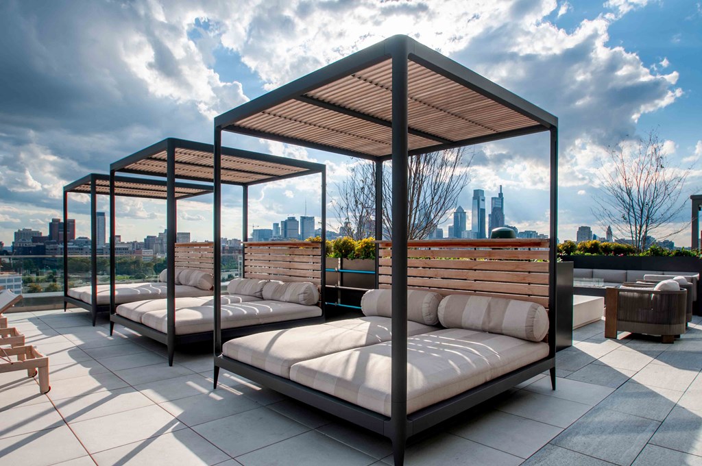 a rooftop lounge area with beds and a city skyline in the background