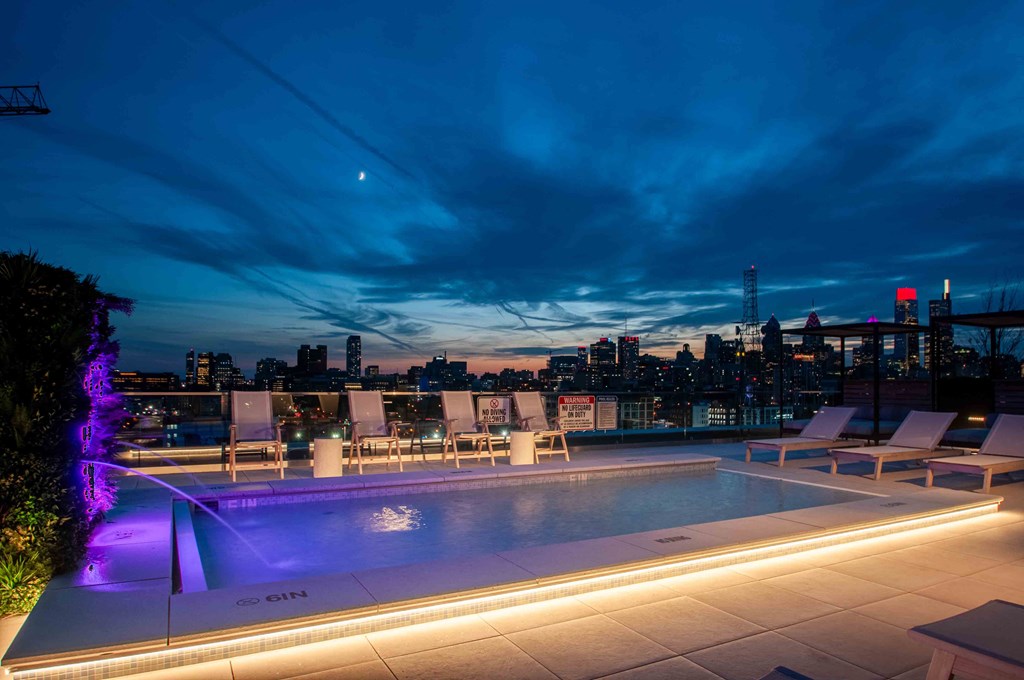 the pool on the roof of the building is lit up at night