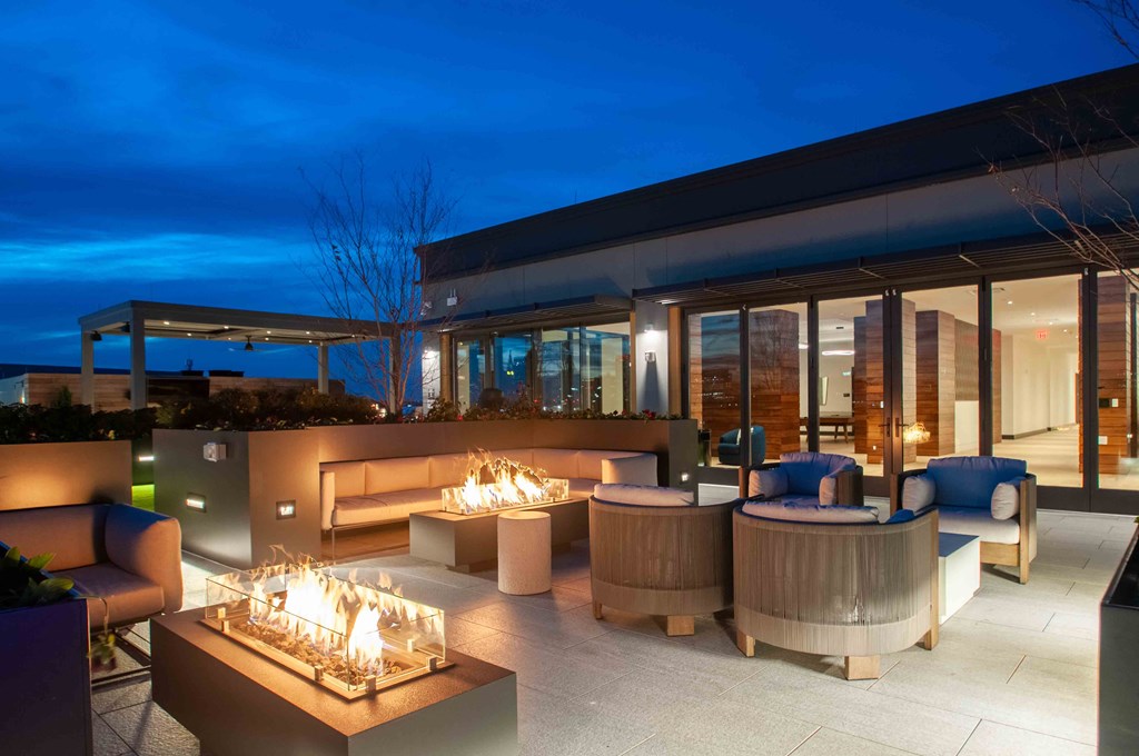 a patio with a fire pit and chairs at night