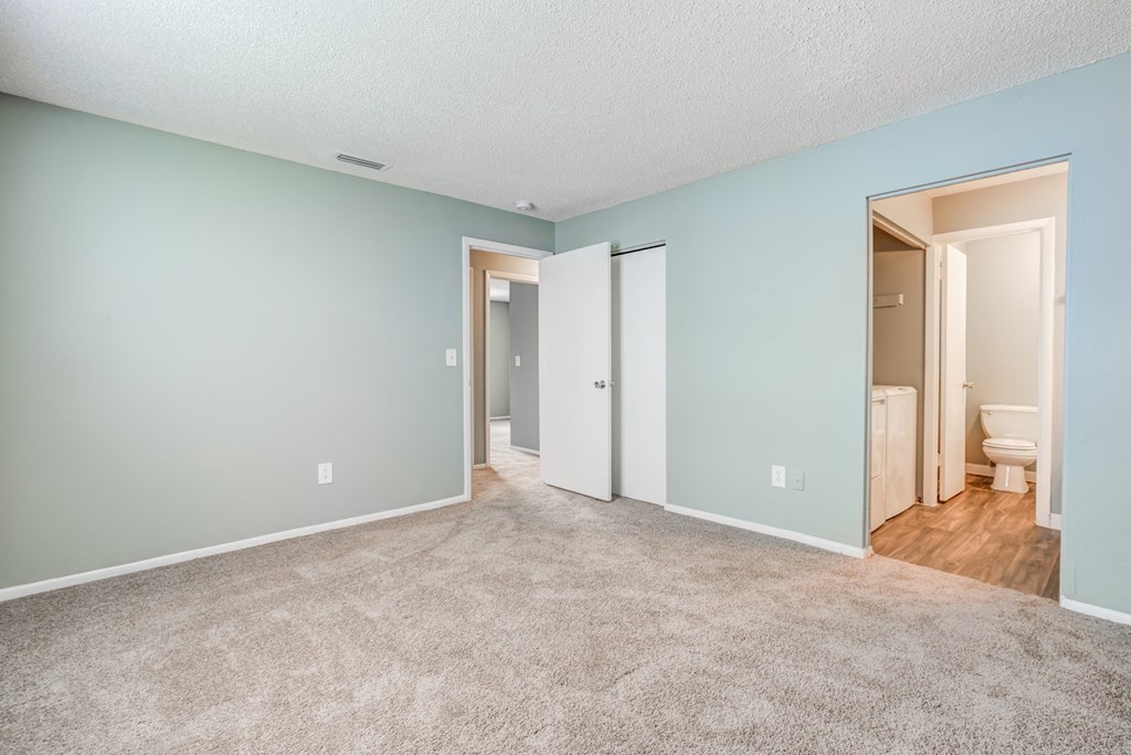 Bedroom with soft plush carpeting, a spacious closet, and an en-suite bathroom at The Commons, a pet-friendly community in Tampa, FL, near Temple Terrace.