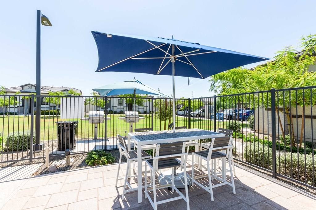 A table with chairs and an umbrella is set up on a patio.