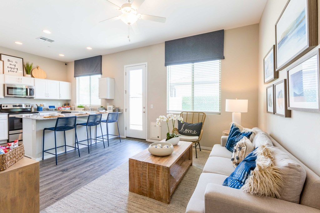 A well-lit, modern living room with a kitchen area in the background.
