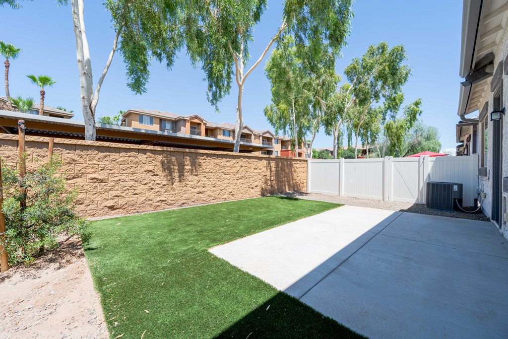 A backyard with a green lawn and a white fence.