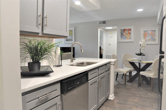 Modern kitchen with gray cabinets, stainless steel appliances, quartz countertops, and dining area.
