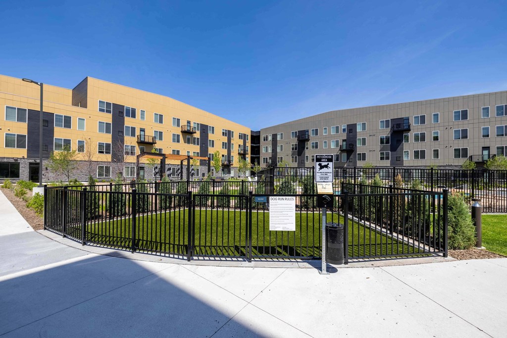 a fenced in grassy area in front of an apartment building
