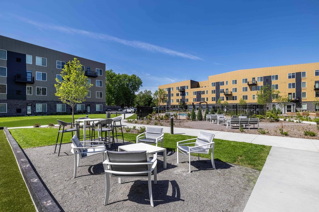 a courtyard with tables and chairs in front of an apartment building