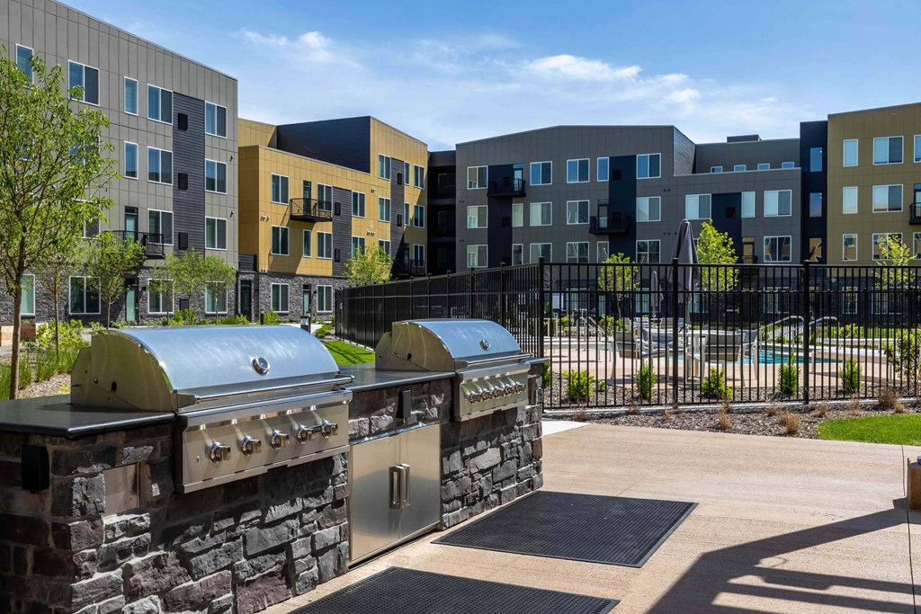 a patio with two grills in front of an apartment building