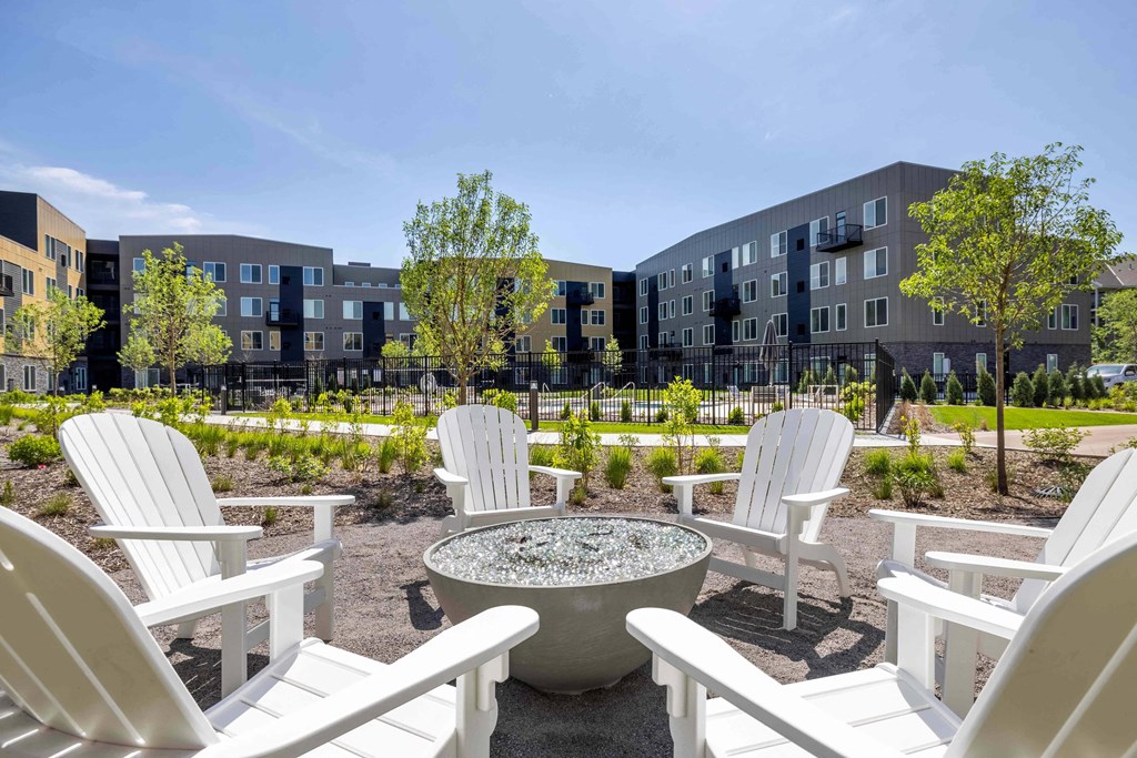 an outdoor patio with white chairs and a fire pit